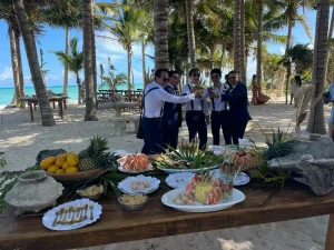 Groom and friends beside a beachfront catering spread with seafood and fresh fruit