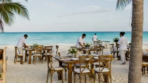 Catering staff preparing dining tables for a private beach event in Cancun