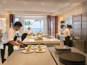 Catering team plating wedding dinner courses in a private Cancun villa kitchen