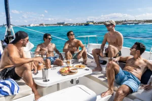 Friends relaxing on a yacht during a Playa del Carmen bachelor party with turquoise water in the background