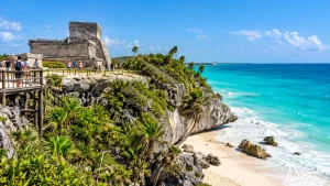 Visitors exploring the Tulum ruins above the turquoise Caribbean Sea